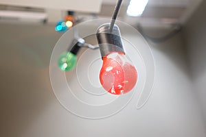 Colorful Incandescent light bulb hanging on black electric wire