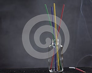 The Colorful incense sticks in glass jars There was a red light that lit up with smoke. Placed on a blurred black gray background
