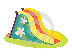 Colorful inflatable slide with floral pattern on grass. Bright yellow, red, and blue bounce slide for kids