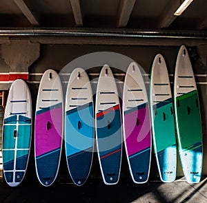 Colorful inflatable stand-up paddle boards SUP by the wall. Surfing and sup boarding equipment close up photo