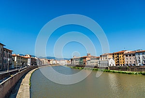 Colorful Italian houses in Pisa, Italy, alongside the embankment of Arno river.