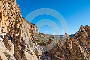 Colorful jagged rock formations, high cliffs, and ancient adobe ruins in Bandelier National Monument