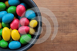 Colorful jelly beans candies in a bowl on wooden background. Sweet holiday treats for kids