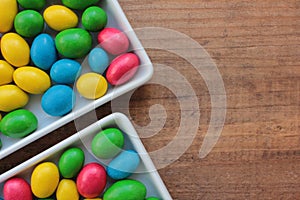 Colorful jelly beans candies in a bowl on wooden background. Sweet holiday treats for kids