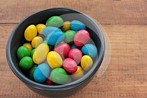 Colorful jelly beans candies in a bowl on wooden background. Sweet holiday treats for kids