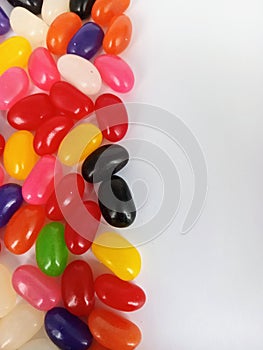 Colorful jelly beans candy on one side of a white background