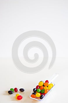 Colorful jelly beans in a clear scoop on white background