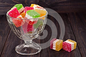 Colorful jelly candy in a glass vase on wooden background