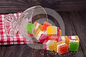 Colorful jelly candy in a glass vase on wooden background