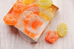colorful jelly candy in golden present box.white wooden table.top view