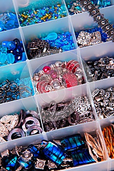 Colorful jewelry beads organized by type and color in a plastic container.