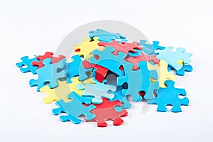 Colorful jigsaw puzzle pieces on a white background. The puzzle pieces are blue, red, and yellow in color and are scattered and