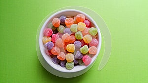 Colorful jujubes on green background top view