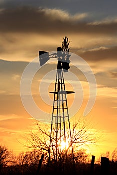 Colorful Kansas Sunset in the evening with clouds and a Windmill silhouette.