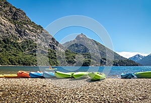 Colorful Kayaks in a lake surrounded by mountains at Bahia Lopez in Circuito Chico - Bariloche, Patagonia, Argentina photo