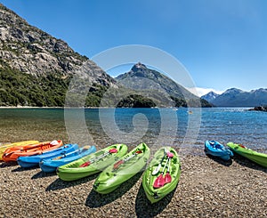 Colorful Kayaks in a lake surrounded by mountains at Bahia Lopez in Circuito Chico - Bariloche, Patagonia, Argentina photo