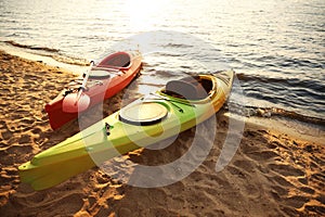 Colorful kayaks near water on river beach at sunset. Summer camp activity