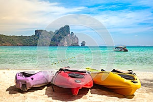 Colorful Kayaks On The Sand. Tropical beach with motor speed boat and cliffs on background. Summer active leisure