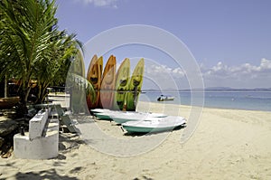 Colorful kayaks on tropical deserted white sandy beach at sunny day.
