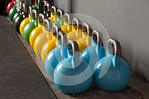 Colorful kettlebells in a row in a gym photo