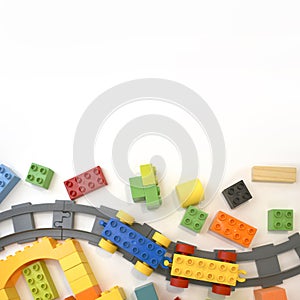 Colorful kids toys border with toy train, railway, plastic and wooden blocks on white background.