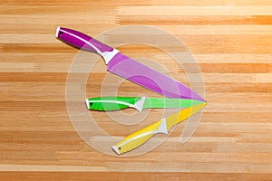 Colorful Kitchen Knives with Different Purposes on Top of a Wooden Cutting Board