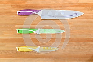 Colorful Kitchen Knives with Different Purposes on Top of a Wooden Cutting Board