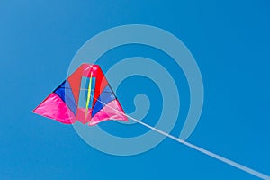 Colorful kite flying against blue sky background