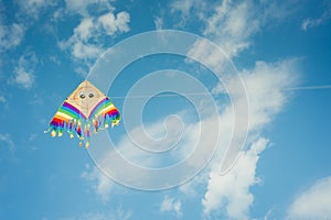 Colorful kite flying against the blue sky with clouds