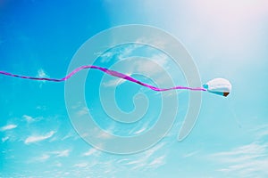 Colorful kite flying in the blue sky through the clouds