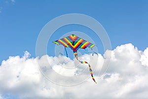 Colorful kite flying in a blue sky with clouds