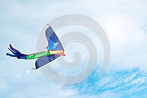 A colorful kite flying in the clouds and sun glares