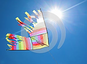 colorful kite flying high in the blue sky and with the sun in th