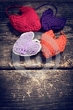 Colorful knitted hearts on the dark old boards