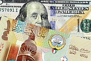 A colorful Kuwaiti quarter dinar with an American one hundred dollar bill close up