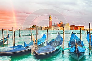 Colorful landscape with sunset sky, rainbow and gondolas parked near piazza San Marco in Venice. Church of San Giorgio Maggiore on