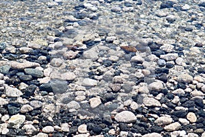 Colorful large pebbles under clear water on the beach of mediterranean sea