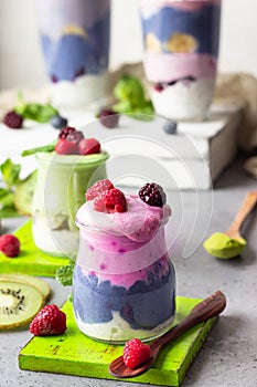 Colorful layered smoothie made of different berries, matcha tee and chia pudding in glasses.