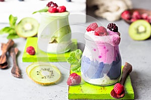 Colorful layered smoothie made of different berries, matcha tee and chia pudding in glasses.