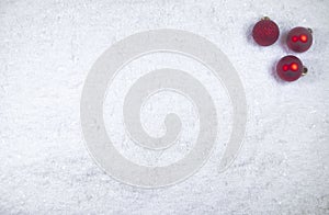 Colorful layout made of three red Christmas tree baubles on icy snow background