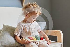 Colorful learning toys. Cognitive development puzzles. Montessori teaching method. Little blonde baby girl palying with wooden