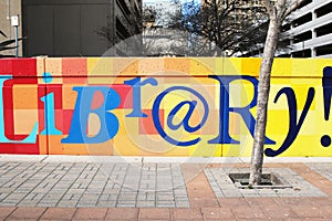 Colorful library sign painted on stone wall outside library in downtown area