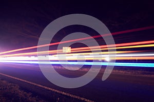 Colorful light beams of moving vehicles on busy highway at dusk