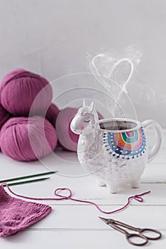 Colorful Llama shaped tea or coffee mug with knitting needles, scissors and wool yarn, steam in form of heart