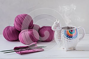 Colorful Llama shaped tea or coffee mug with steam with knitting needles, scissors and wool yarn
