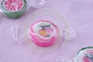 Colorful lollipops and different colored fruit round candy in wrapper on pink background