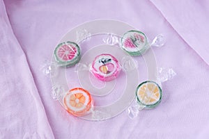 Colorful lollipops and different colored fruit round candy in wrapper on pink background