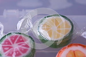 Colorful lollipops and different colored fruit round candy in wrapper in container