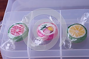 Colorful lollipops and different colored fruit round candy in wrapper in container