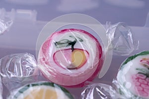 Colorful lollipops and different colored fruit round candy in wrapper in container